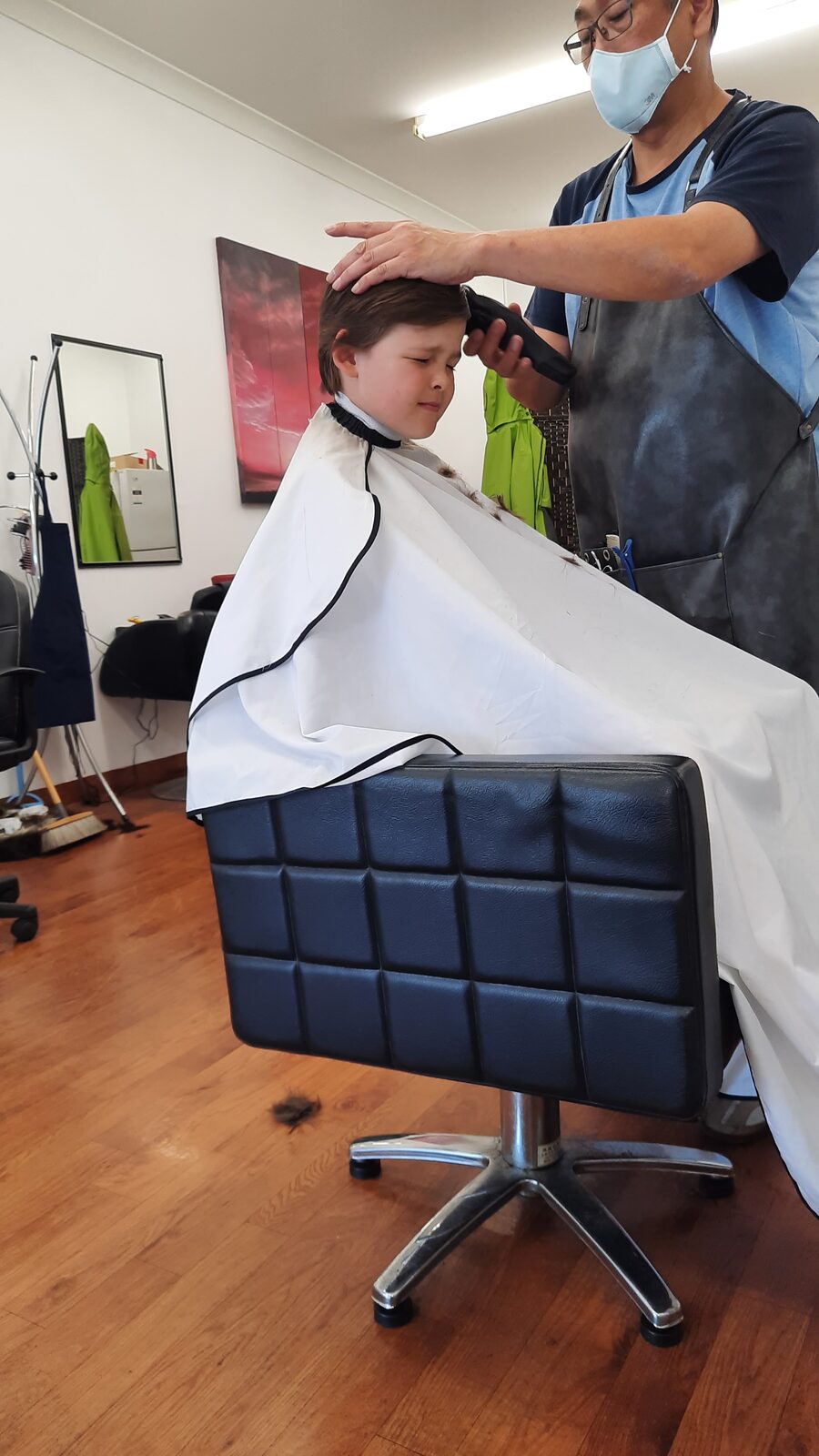 A barber steadying a young boy's head during a clipper cut