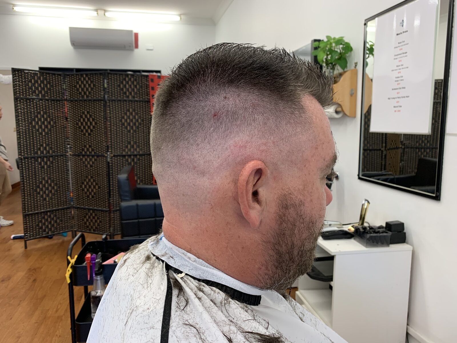 A customer with a freshly faded short back and sides and a trimmed beard