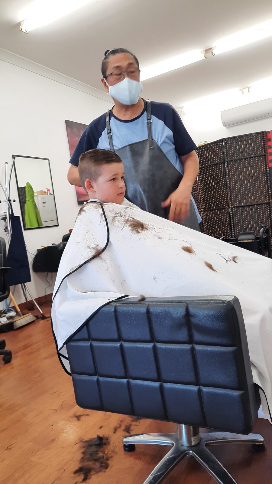 A barber at Hair Cuts by Misty cutting a young boy's hair