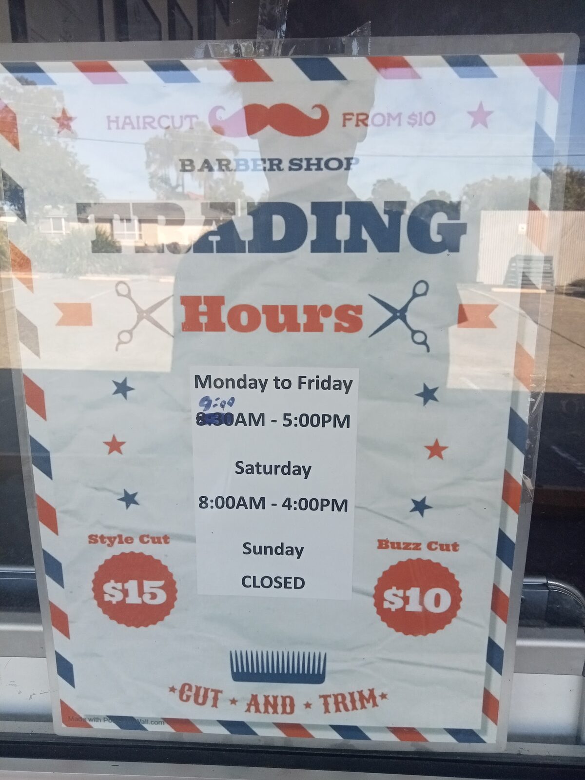 The Trading Hours sign in the shop window, showing a $15 style cut and a $10 buzz cut